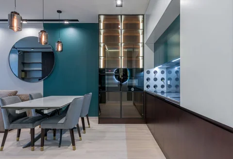 A marble dining table, upholstered chairs and amber pendants against deep teal walls